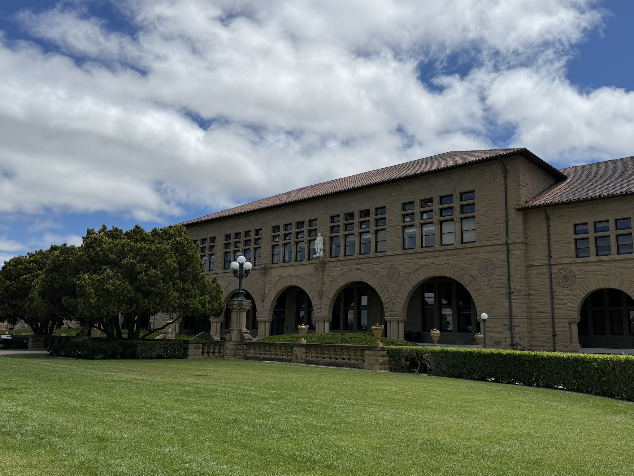 Arched campus building and green lawn at Stanford University